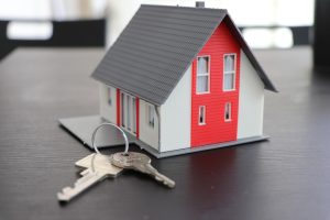 Model domku z czerwonym dachem obok kluczy symbolizujący kredyt hipoteczny
