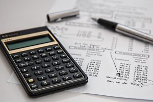 Kalkulator finansowy leżący na dokumentach z wyliczeniami obok długopisu