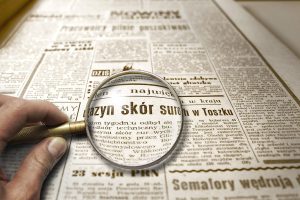 Lupa powiększająca tekst w starej gazecie, symbolizująca dokładne sprawdzanie informacji